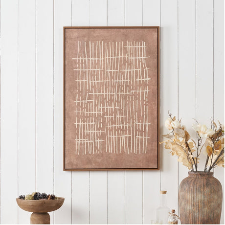 Canvas wall art with abstract cream linear crosshatch design on a brown background, framed in oak-effect wood, displayed on a white panelled wall above a wooden bowl and vase.