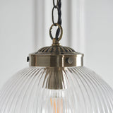 Close-up of the Endon Ashmere pendant showing the antique brass fitting, decorative cap and chain link above a ribbed clear glass shade.