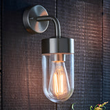 Endon Castfield outdoor wall light in brushed silver steel with a clear glass casing and exposed filament E27 bulb, mounted on a dark timber wall.