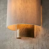 Close-up of the Endon Brenwood wall light showing its hammered aged bronze fitting and natural linen-effect fabric shade against a textured grey wall.