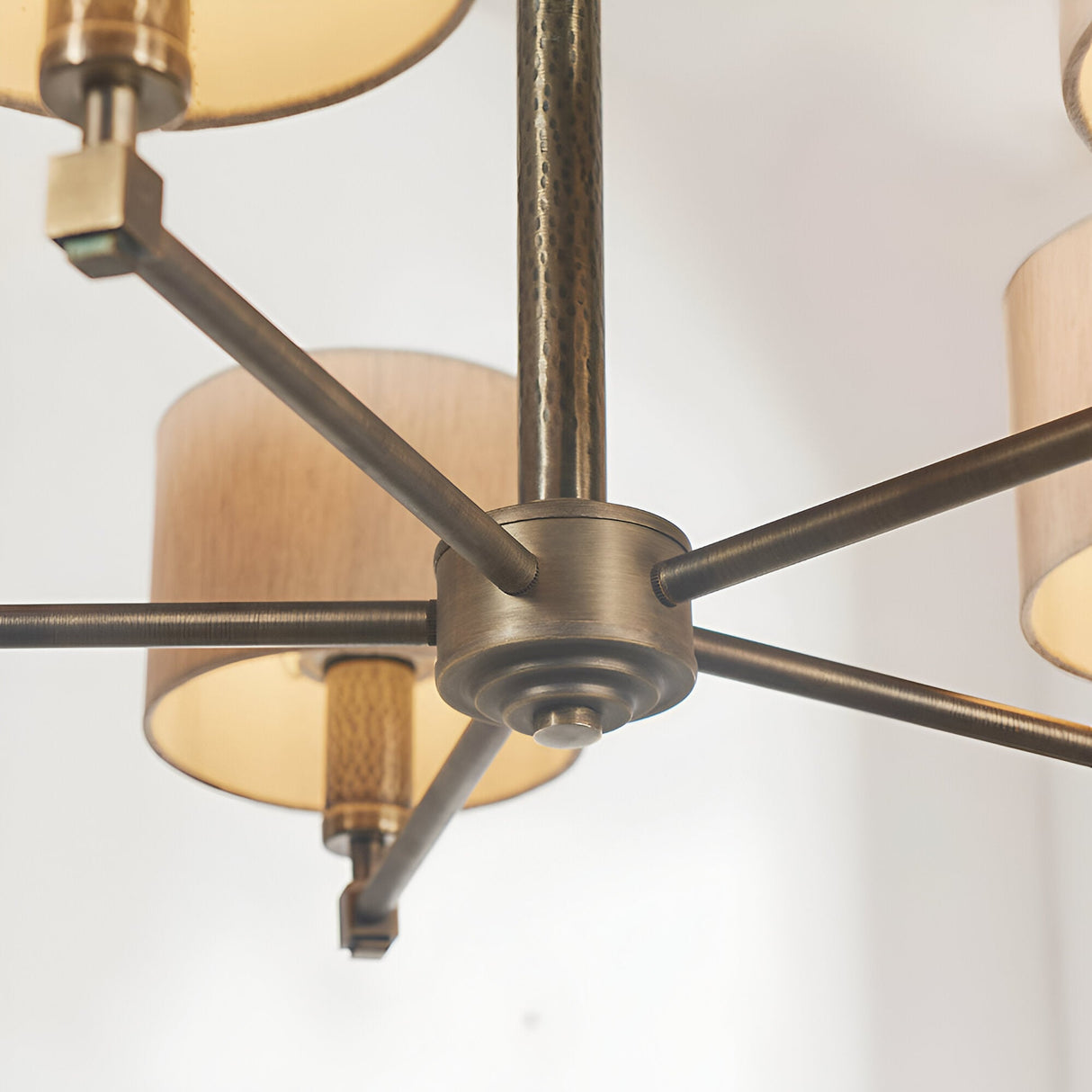 Close-up of the Endon Brenwood 5 Light Pendant showing the hammered bronze centre plate, radiating arms and natural linen effect fabric shades.