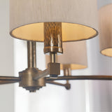 Close-up of Endon Brenwood pendant showing hammered bronze lampholder, aged bronze arms and natural linen effect drum shades with warm inner glow.