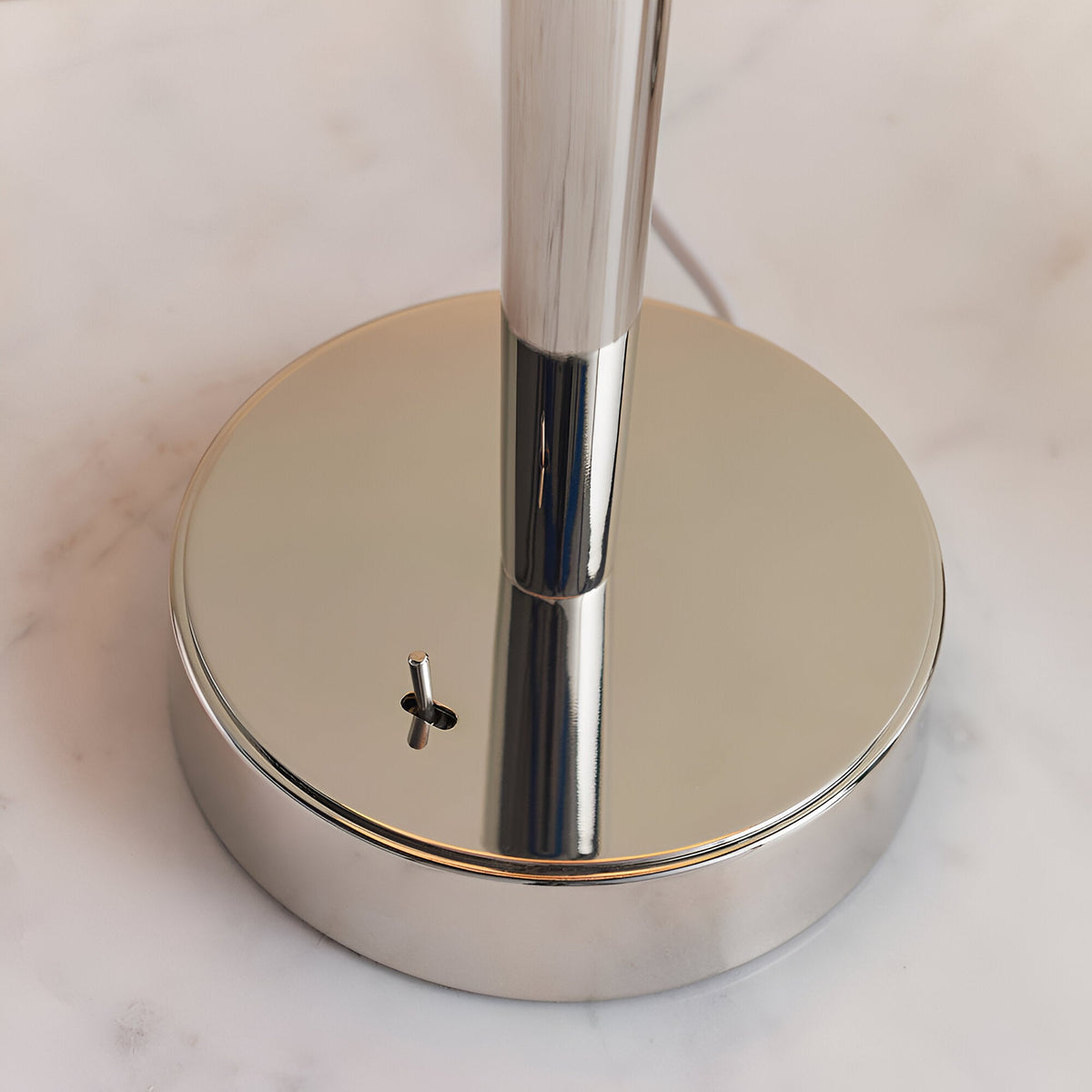 Close-up of the Endon Crandale USB table lamp base in bright nickel plate, showing the toggle switch and slim upright stem on a marble surface.