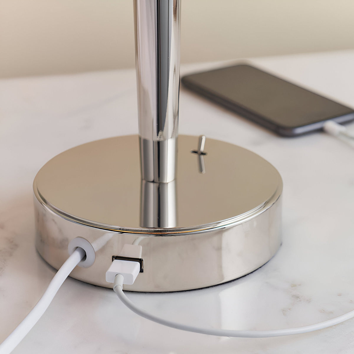 Close-up of the Endon Crandale table lamp's nickel base with built-in USB port charging a phone via white cable on a marble surface.