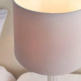 Close-up of the Endon Crandale table lamp's mink faux silk drum shade, illuminated to show its warm glow against a soft neutral interior.