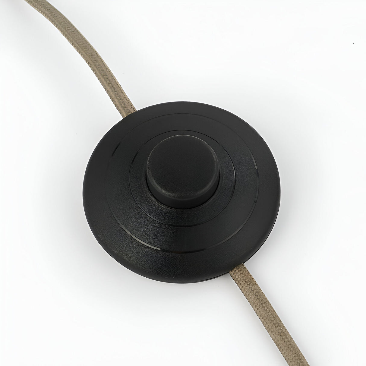 Close-up of the round matte black inline foot switch on the Brockfield Floor Lamp's fabric cable, shown on a white background.
