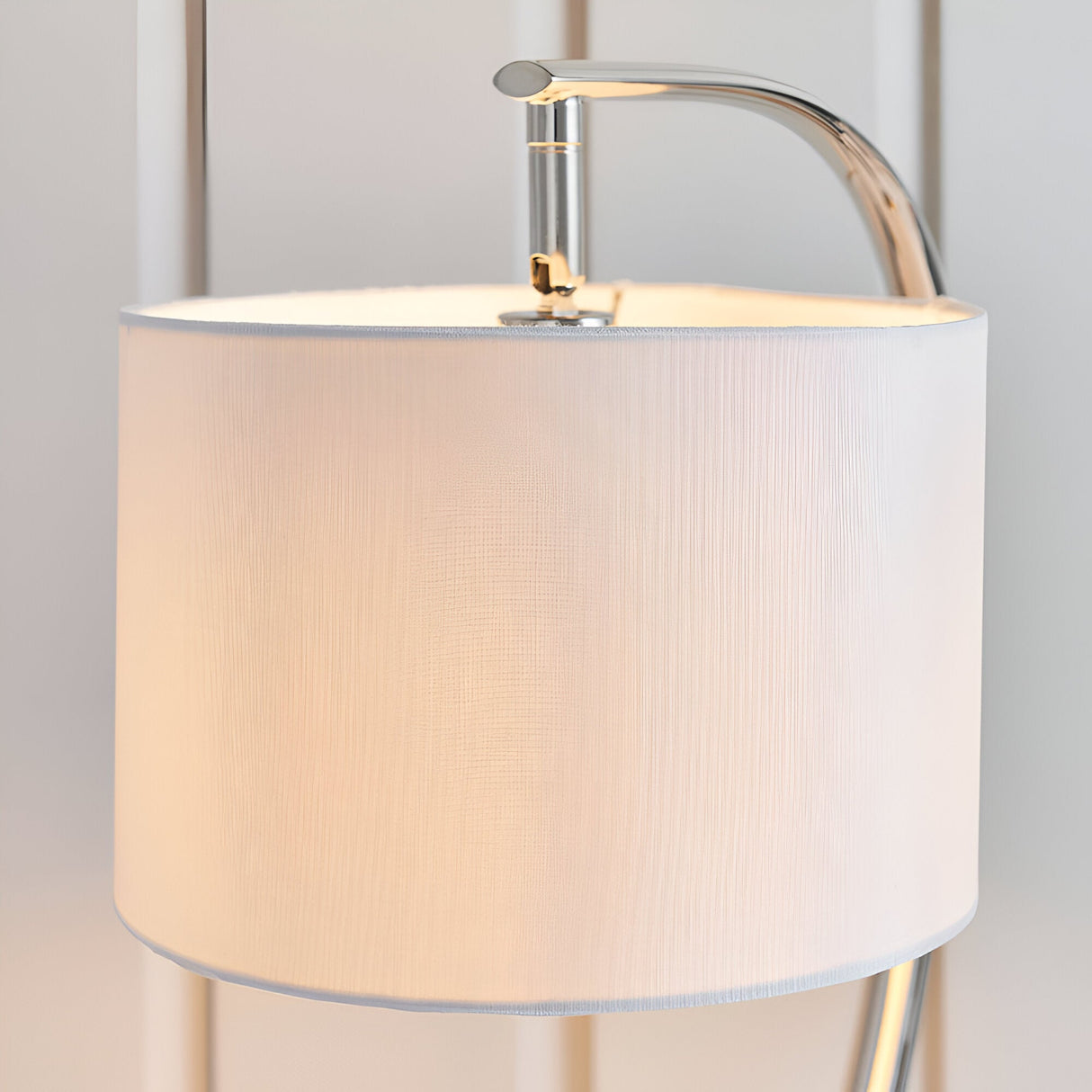 Brockfield Table Lamp in nickel with an arched chrome stem and white faux silk drum shade, close-up view against a plain light background.