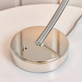 Close-up of the Brockfield Table Lamp's round nickel-plated base with curved metal stem and screw fitting, set on a light surface.