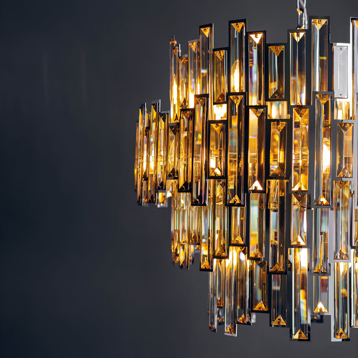 Endon Danedale 15 light chandelier in polished chrome with tiered tinted champagne bevelled crystals, illuminated against a dark grey background.