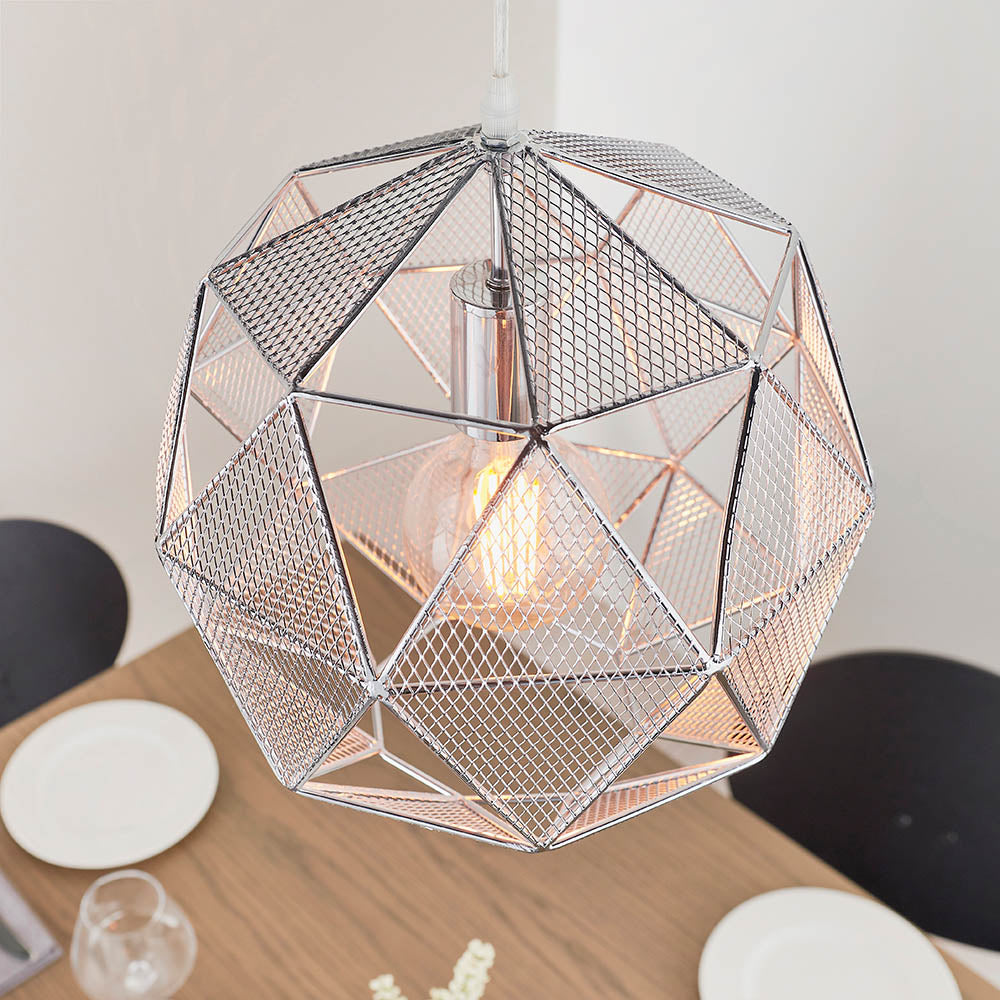 Aldford Pendant in polished chrome, a geometric mesh-triangle shade with visible bulb, hanging above a dining table in a light-toned room.