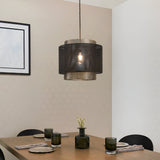 Chartfield Pendant in matt black mesh with antique brass inner shade, hung above a dining table with a lit E27 bulb visible.
