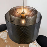 Chartfield Pendant in Brass & Black, showing nested mesh metal cylinder shades with antique brass inner and matt black outer layer, lit above a dining table.