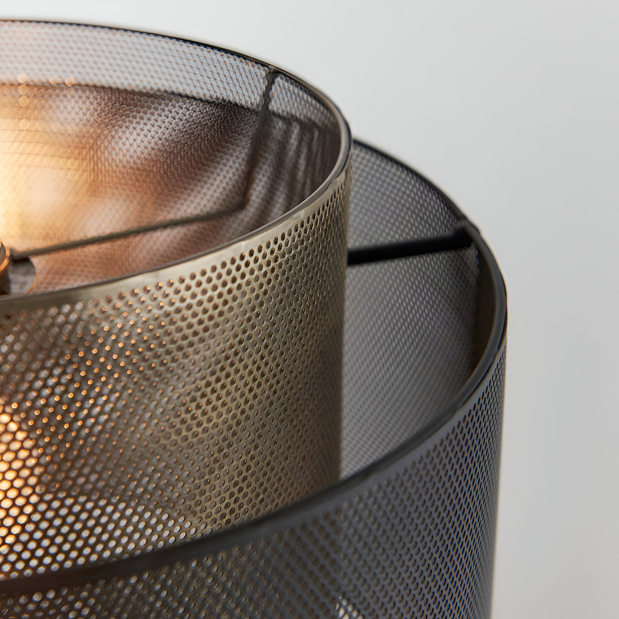 Close-up of the Chartfield Pendant in brass and black, showing double perforated mesh cylinder shades with a lit E27 bulb visible inside.