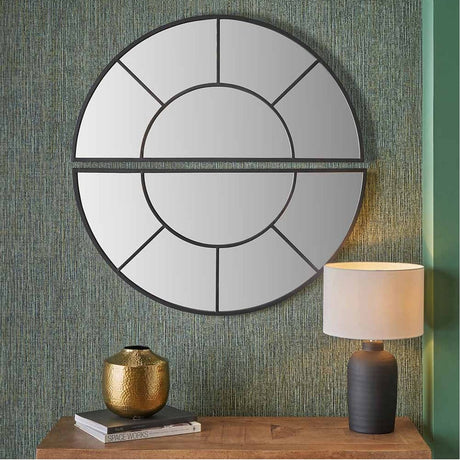 Round black iron wall mirror, 92 x 92cm, with segmented glass panels divided by a horizontal bar, shown above a wooden console table with a lamp and vase.