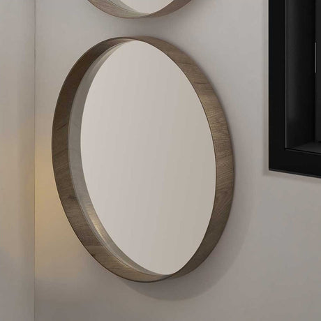 Round wall mirror with a deep wood veneer edge in a natural grain finish, mounted on a light wall beside a second mirror and dark-framed window.