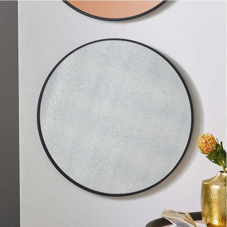 Round wall mirror with black frame and foxed glass, 74 x 74cm, shown on a light wall in a hallway setting.