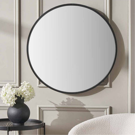 Round black-framed wall mirror, 74 x 74cm, with wood veneer edge, hung on a panelled wall above a side table with a black vase and white flowers.