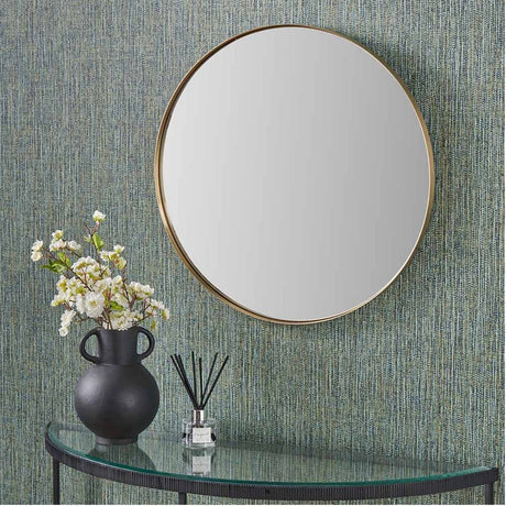 Round wall mirror with a slim brushed gold frame, 80 x 80cm, hung above a glass console table with a black vase and dried florals in a hallway setting.