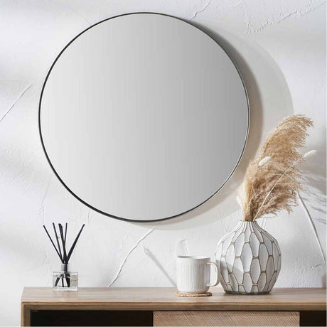 Round wall mirror with a slim brushed silver metal frame, 80 x 80cm, shown above a wooden sideboard with a vase and mug in a hallway setting.