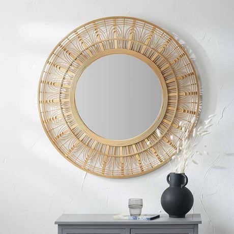Round wall mirror with a natural bamboo frame featuring layered decorative patterning, 90 x 90cm, shown above a grey sideboard with a black vase and glass.