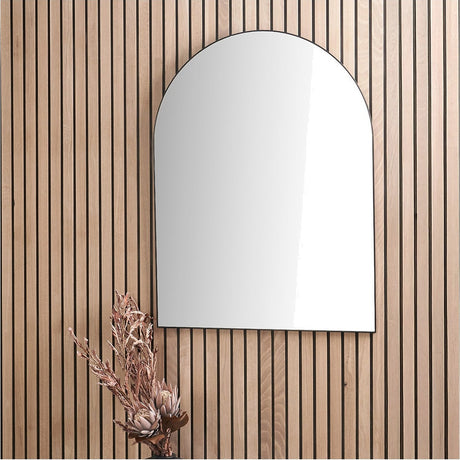 Slim frame black metal tall arch wall mirror, 90 x 120cm, mounted on a wood-slat panelled wall with a dried floral arrangement below.