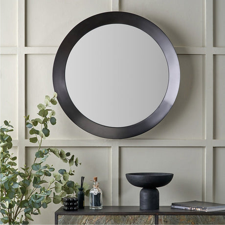 Round wall mirror in graphite aluminium with an angled frame profile, 80 x 80cm, shown above a dark console in a living room setting.