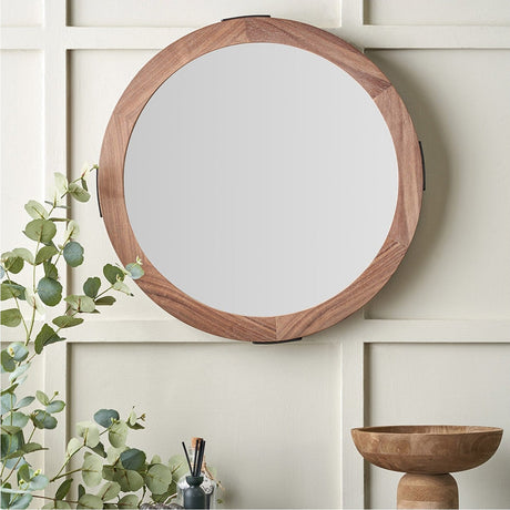Vermont Light Walnut Wood Veneer Round Wall Mirror, 65 x 65cm, with slim wooden frame, shown mounted on a panelled wall above a console with a wooden bowl and greenery.