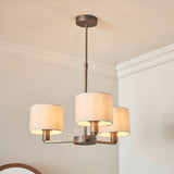 Endon Bexley 3 light pendant in antique bronze with three marble-effect faux silk drum shades on curved arms, shown hanging from a ceiling.