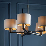 Endon Bexley 5 light pendant in bronze with marble-effect faux silk drum shades on curved arms, shown against a panelled dark blue wall.