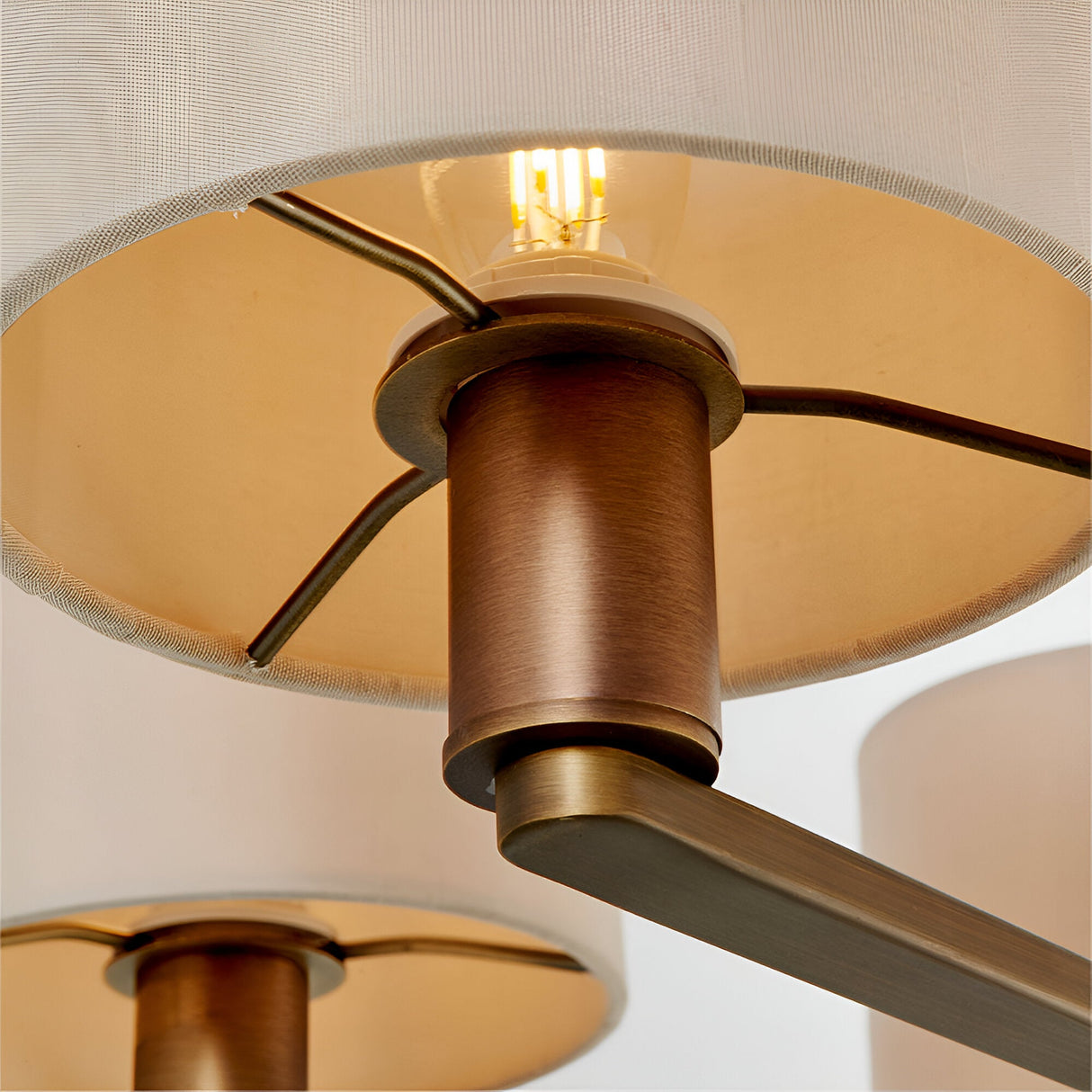 Close-up of Endon Bexley 5 Light Pendant in bronze, showing curved arm, antique bronze fitting, E14 lit bulb, and marble-effect faux silk shade interior.