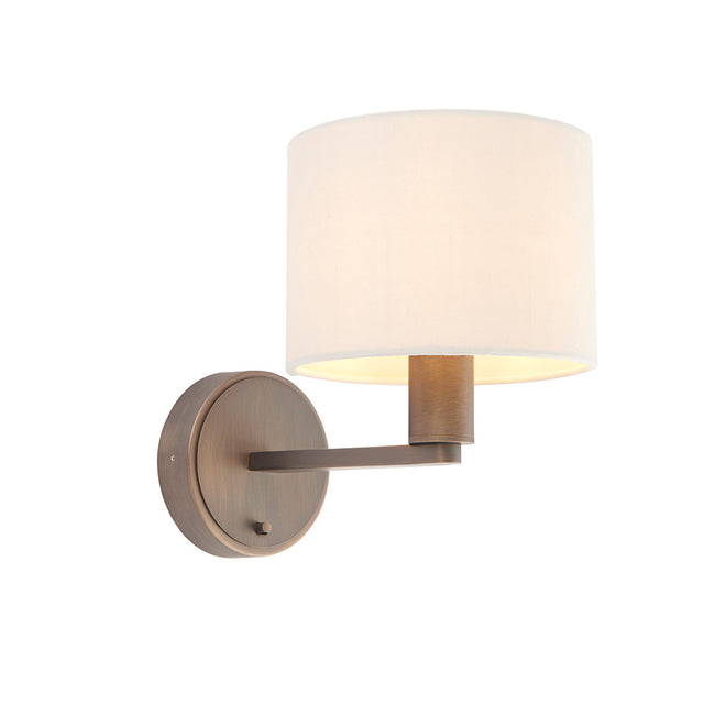Endon Bexley wall light with a bronze brushed arm and circular backplate, topped with a white drum fabric shade, on a plain white background.