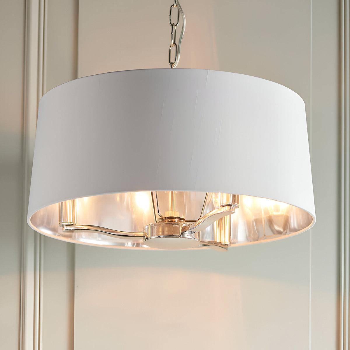 Endon Brendale 3 light pendant with white faux silk drum shade, nickel interior and three E14 lamps, suspended from a chain against panelled walls.