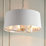 Endon Brendale 3 light pendant with white faux silk drum shade, nickel interior and three E14 lamps, suspended from a chain against panelled walls.
