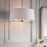 Endon Brendale 3-light pendant with white faux silk drum shade and nickel interior on chain suspension, hung against panelled grey walls beside a silver mirror.