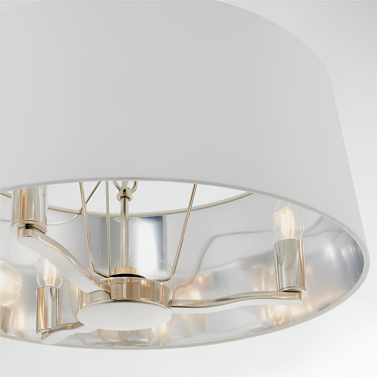 Close-up of Endon Brendale 3 light pendant showing nickel arms, E14 lamps and white faux silk shade with silver metallic lining against a pale background.