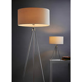 Endon Cranwell floor lamp with chrome tripod frame and cream linen drum shade, shown lit beside a matching table lamp in a dark modern interior.