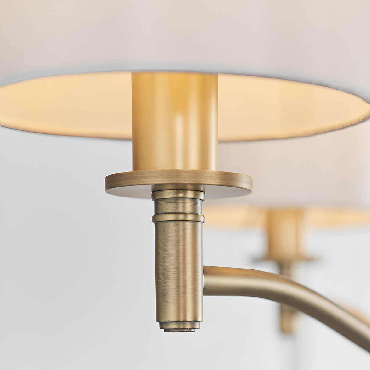 Close-up of Endon Castwell pendant light detail showing matt antique brass lampholder and arm beneath vintage white faux silk shades.