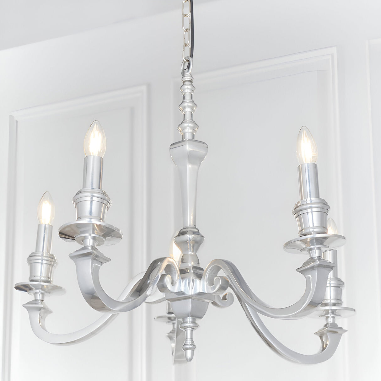 Endon Brambourne 5 light pendant in polished aluminium with curved arms and candle-style lamps, suspended from a chain against white panelled walls.