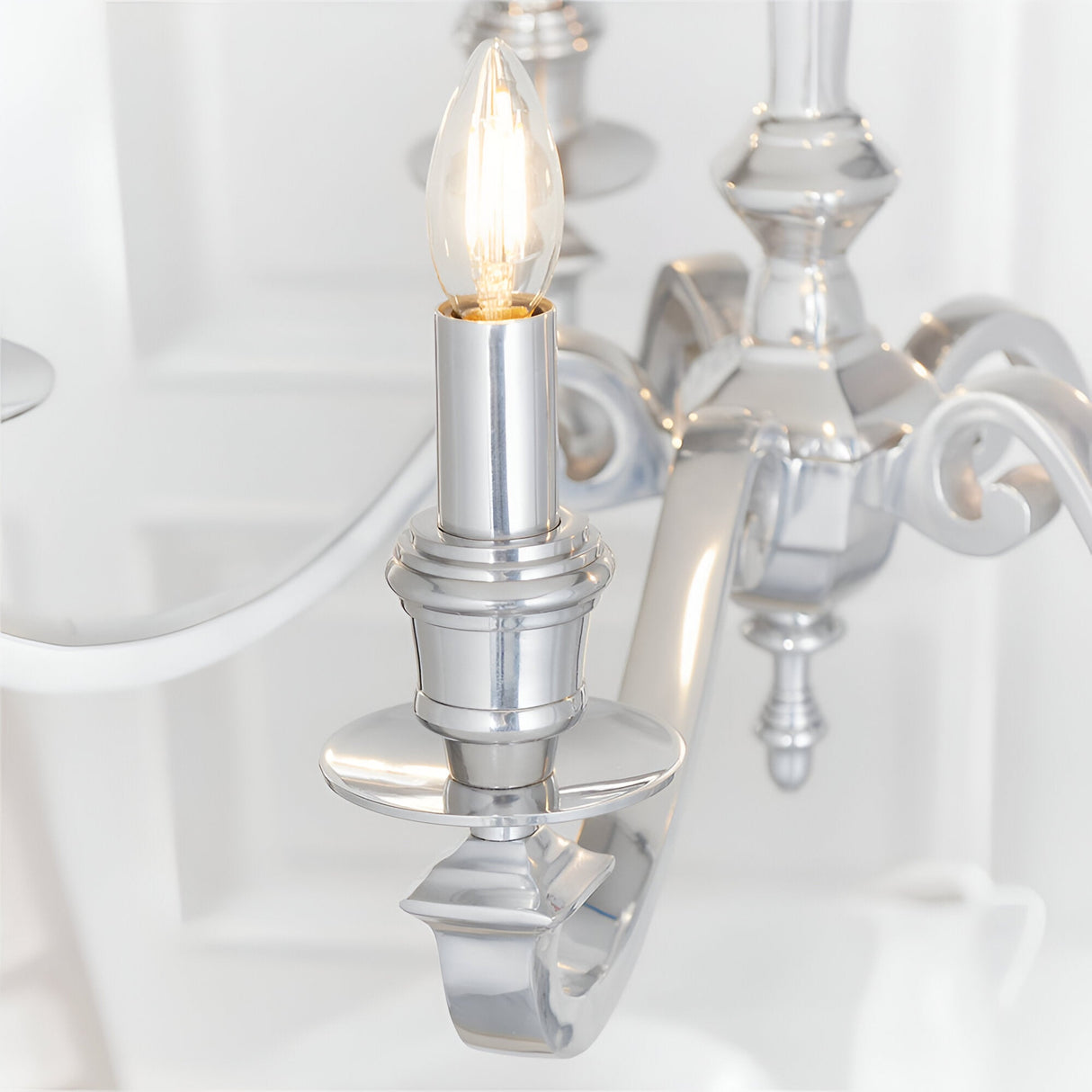 Close-up of Endon Brambourne 5 Light Pendant in polished aluminium, showing a candle-style E14 lampholder with lit bulb on a curved scrolled arm.