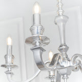 Close-up of the Endon Brambourne 5 Light Pendant in polished aluminium, showing curved arms with candle-style E14 lampholders against a white ceiling.