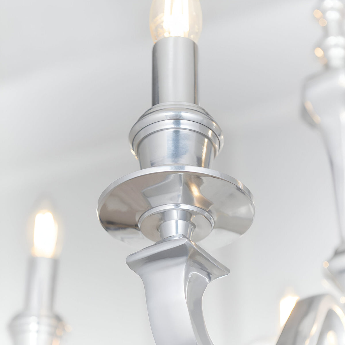 Close-up of the Endon Brambourne pendant showing a polished aluminium candle arm, tiered central column and lit E14 candle-style bulb above.