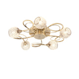 Endon Harcourt 5 light semi-flush ceiling light in antique brass, with curled arms and mesh-caged glass globe shades on a plain white background.