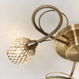 Close-up of Endon Harcourt semi-flush ceiling light showing an antique brass looped arm and beaded mesh globe shade against a white ceiling.
