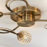 Close-up of Endon Harcourt 3 Light semi-flush ceiling light showing antique brass central fitting, curved arms and a beaded glass globe shade.