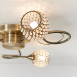 Endon Harcourt 3 light semi-flush ceiling light in antique brass, close-up of two beaded crystal globe shades on curved arms against a white ceiling.