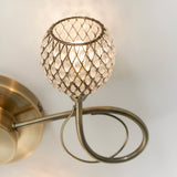 Close-up of Endon Harcourt semi-flush ceiling light arm in antique brass with a beaded glass globe shade and curled decorative detail.