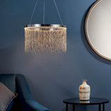 Danestead Pendant in polished chrome, a round LED ring with cascading fine chains, hung above a side table near a round mirror and blue sofa.