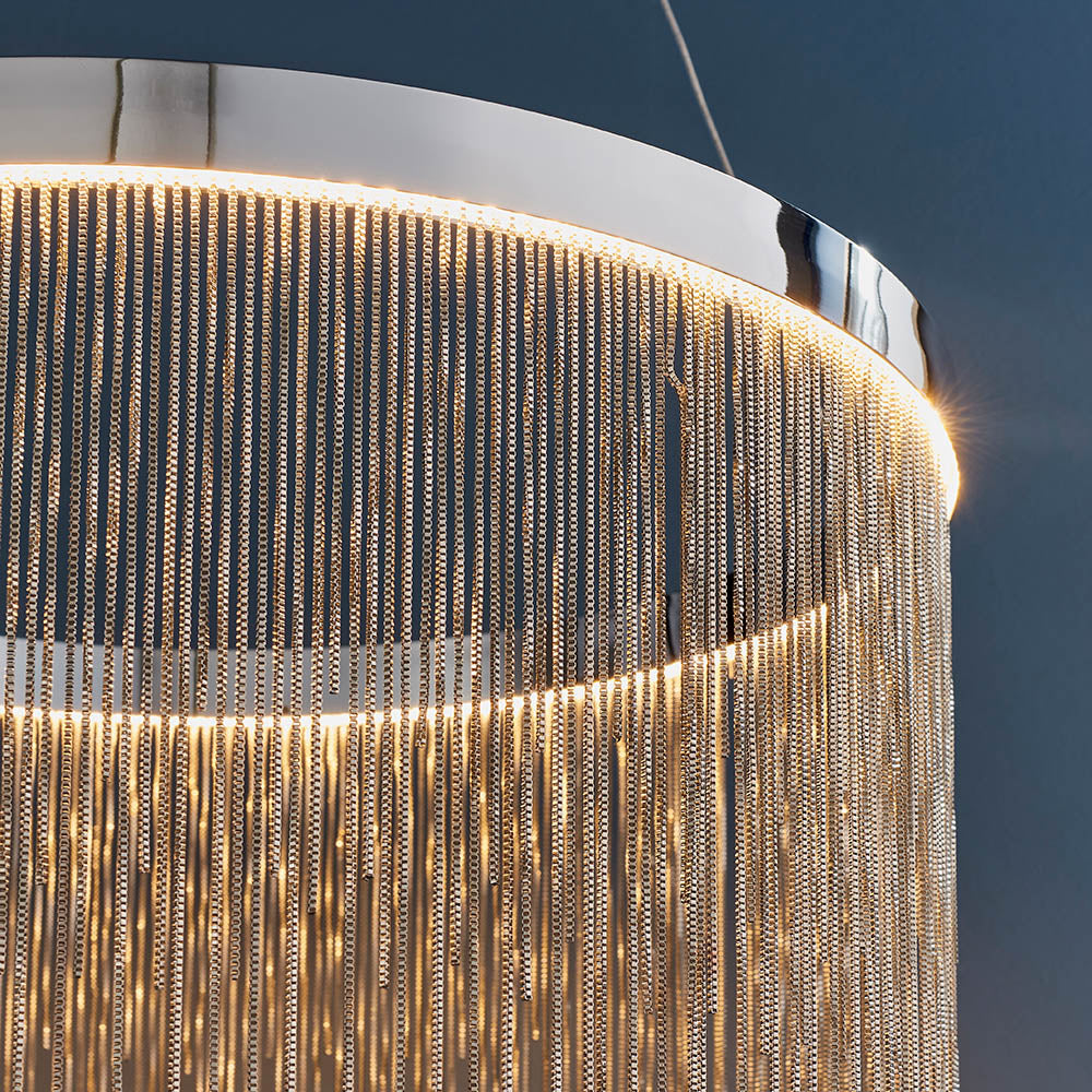 Danestead Pendant in polished chrome, close-up of fine chain strands cascading from a ring of integrated LED light, set against a dark background.
