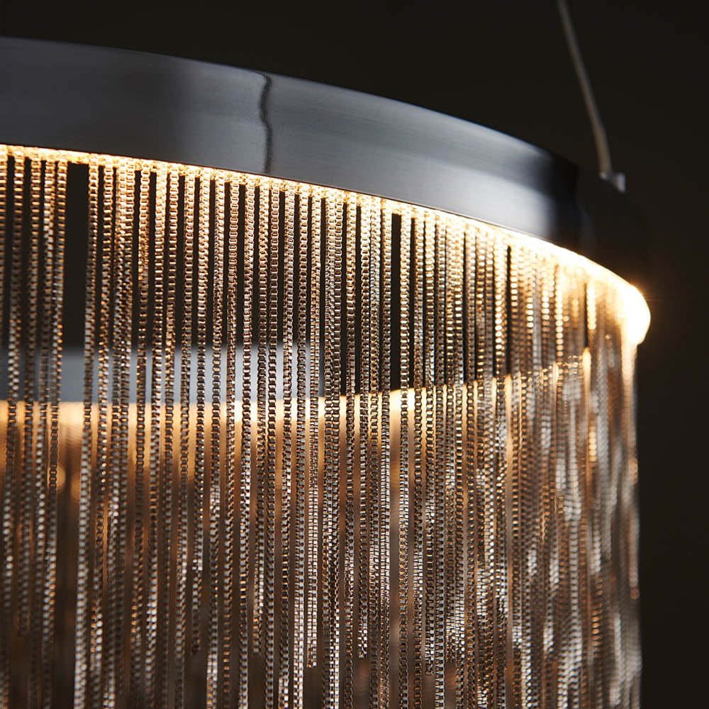 Danestead Pendant in polished chrome, close-up of the ring housing with a cascade of fine chains catching a warm LED glow.