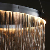 Danestead Pendant in polished chrome, close-up of the ring housing with a cascade of fine chains catching a warm LED glow.